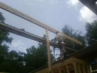 Carpenter setting a ridge beam over a new addition frame — Ice Dam Removal by Roofing Brothers in Terrebonne