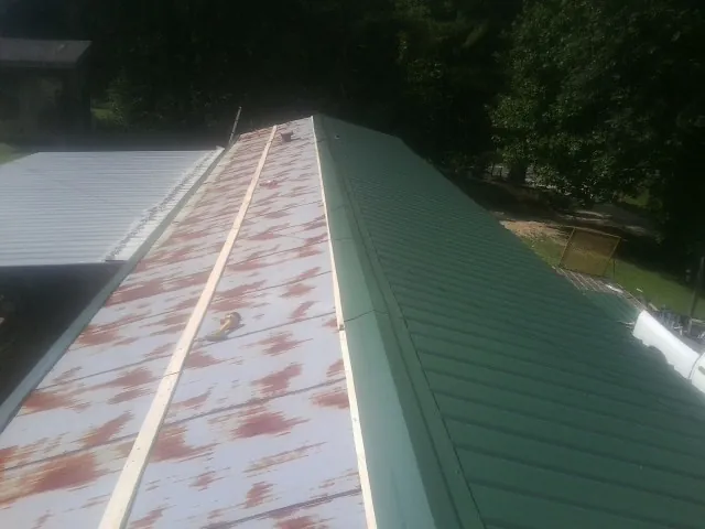Old rusted panels beside newly installed green metal roofing — Wind Damage Roof Repair by Roofing Brothers in Terrebonne