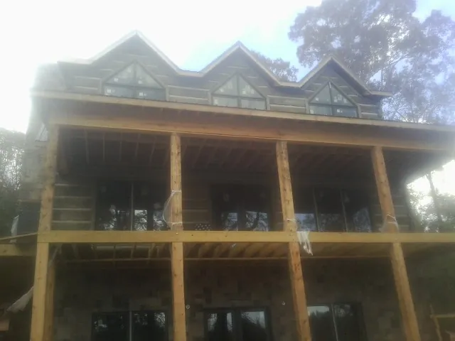 Dormers and porch framing on a large log home under construction — Roof Coating work by our crew in Terrebonne