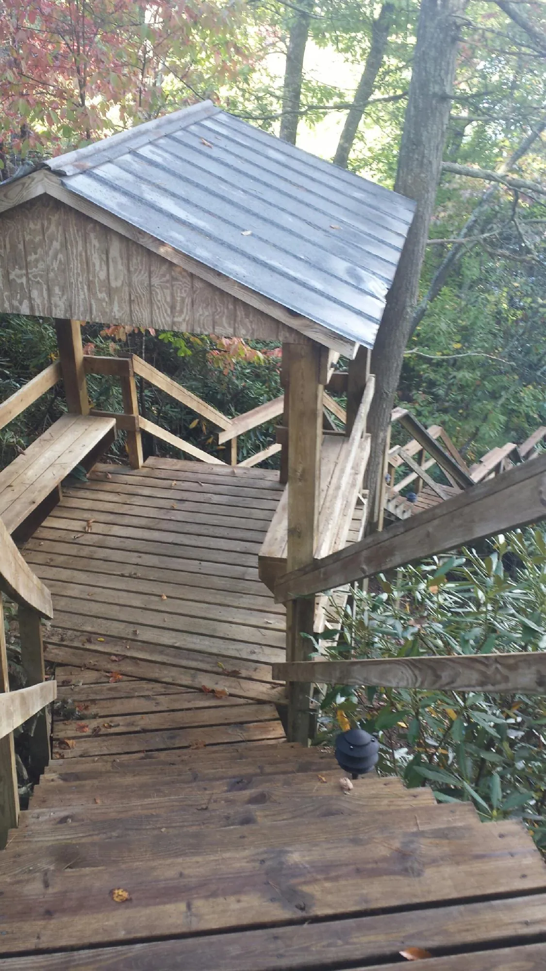 Metal roofed shelter over wooden steps on a wooded walkway — Skylight Repair & Installation work by our crew in Terrebonne