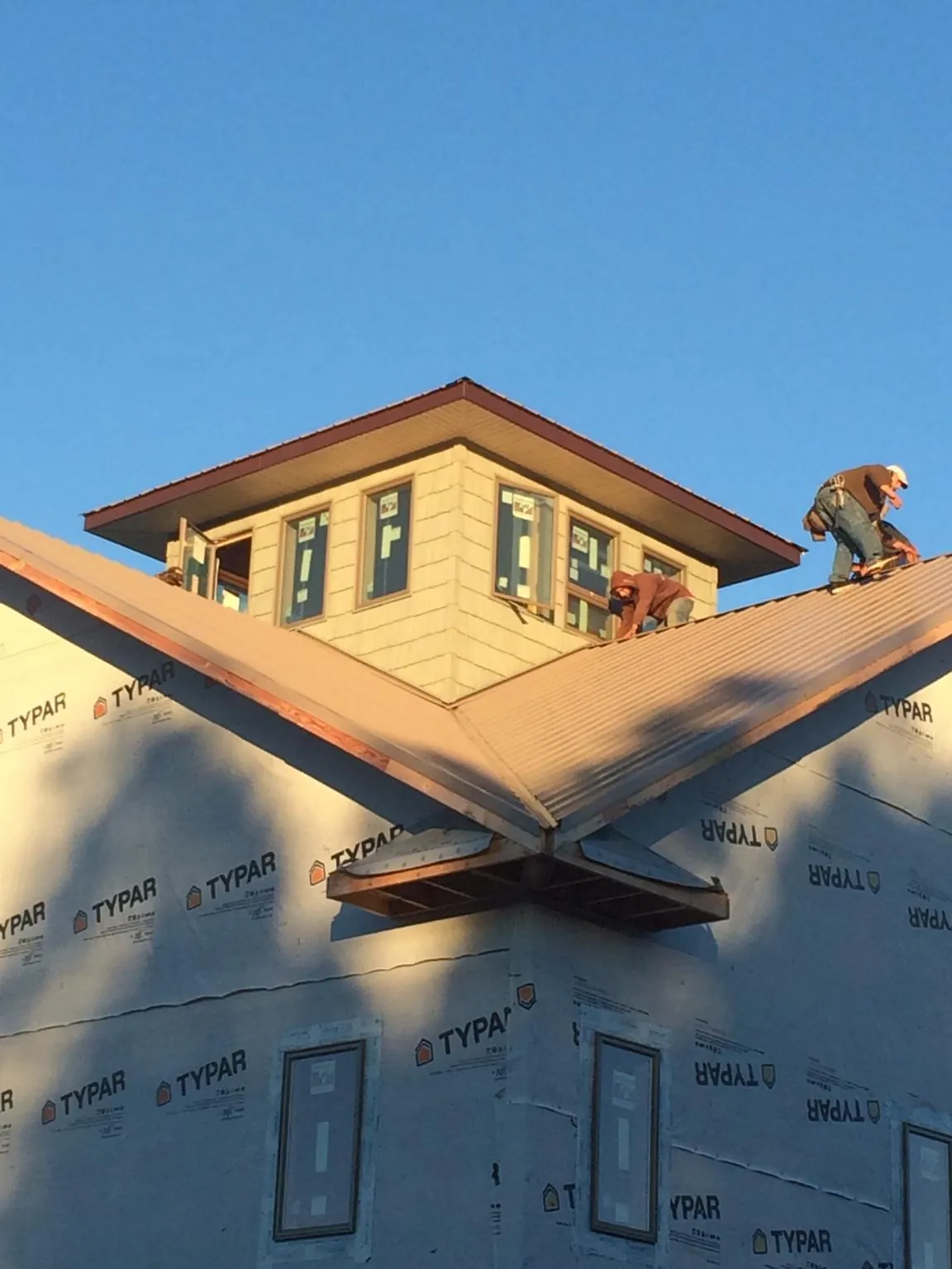 Roofers working around a rooftop cupola on a new metal roof at sunset — Roof Waterproofing in Terrebonne by Roofing Brothers